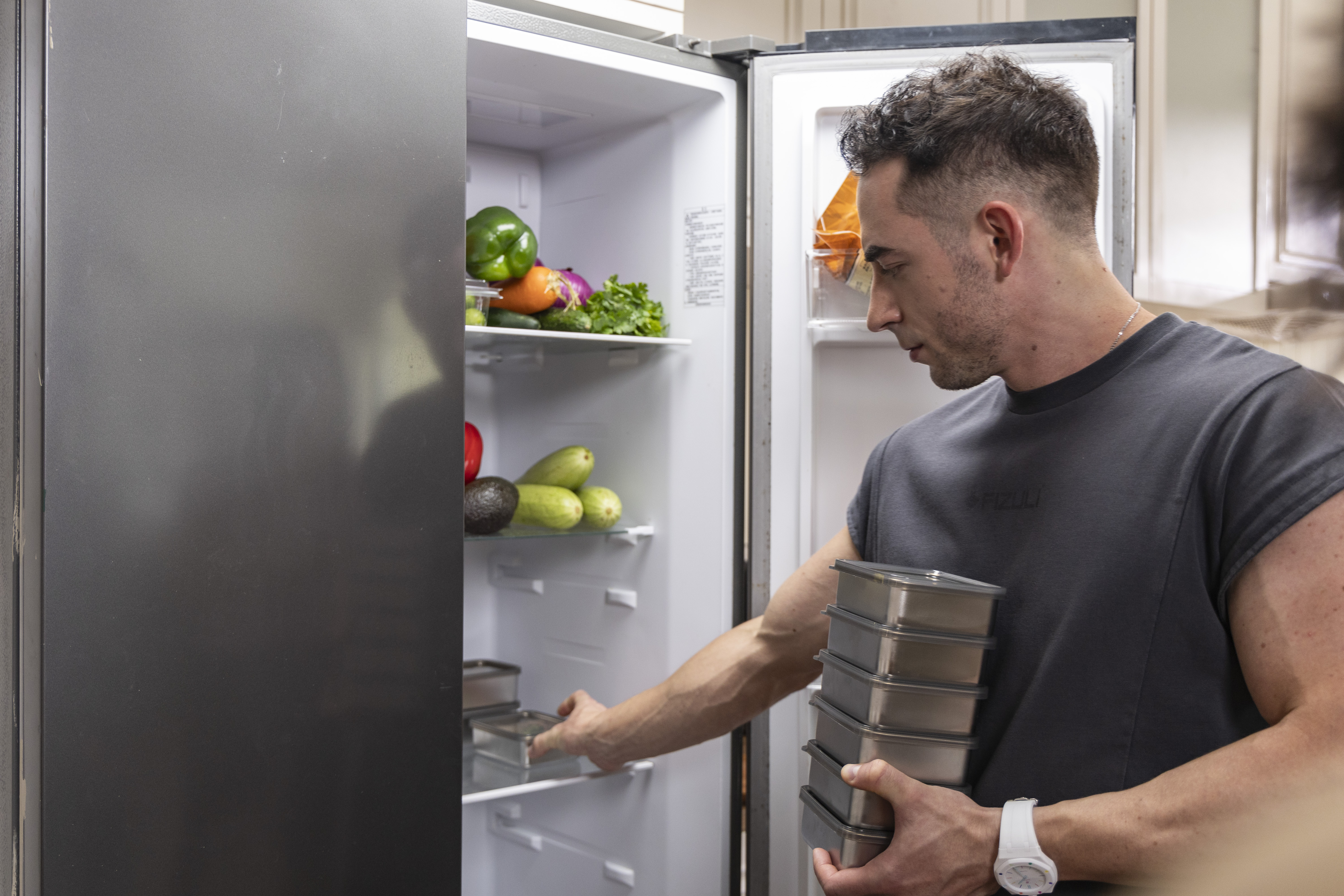 Covered stainless steel PrepTop containers stacked inside a refrigerator